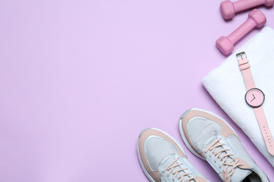 Flat lay composition with woman's sneakers and fitness items on lilac background, space for text