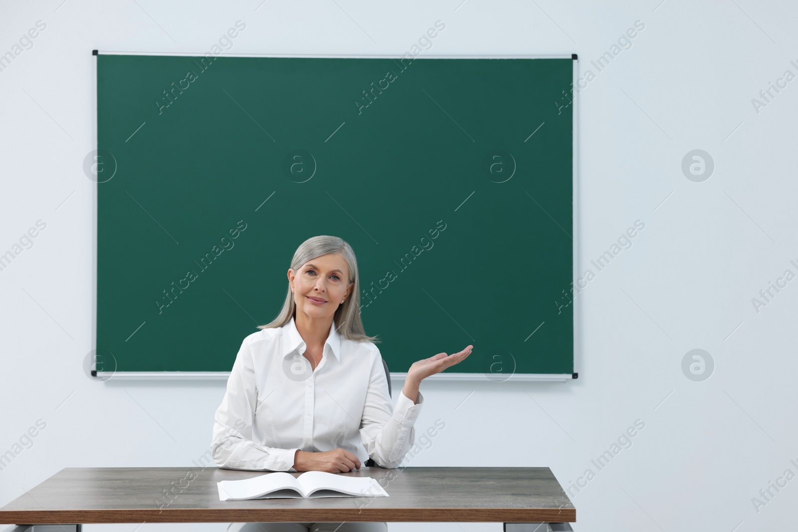 Photo of Professor giving lecture at desk in classroom, space for text