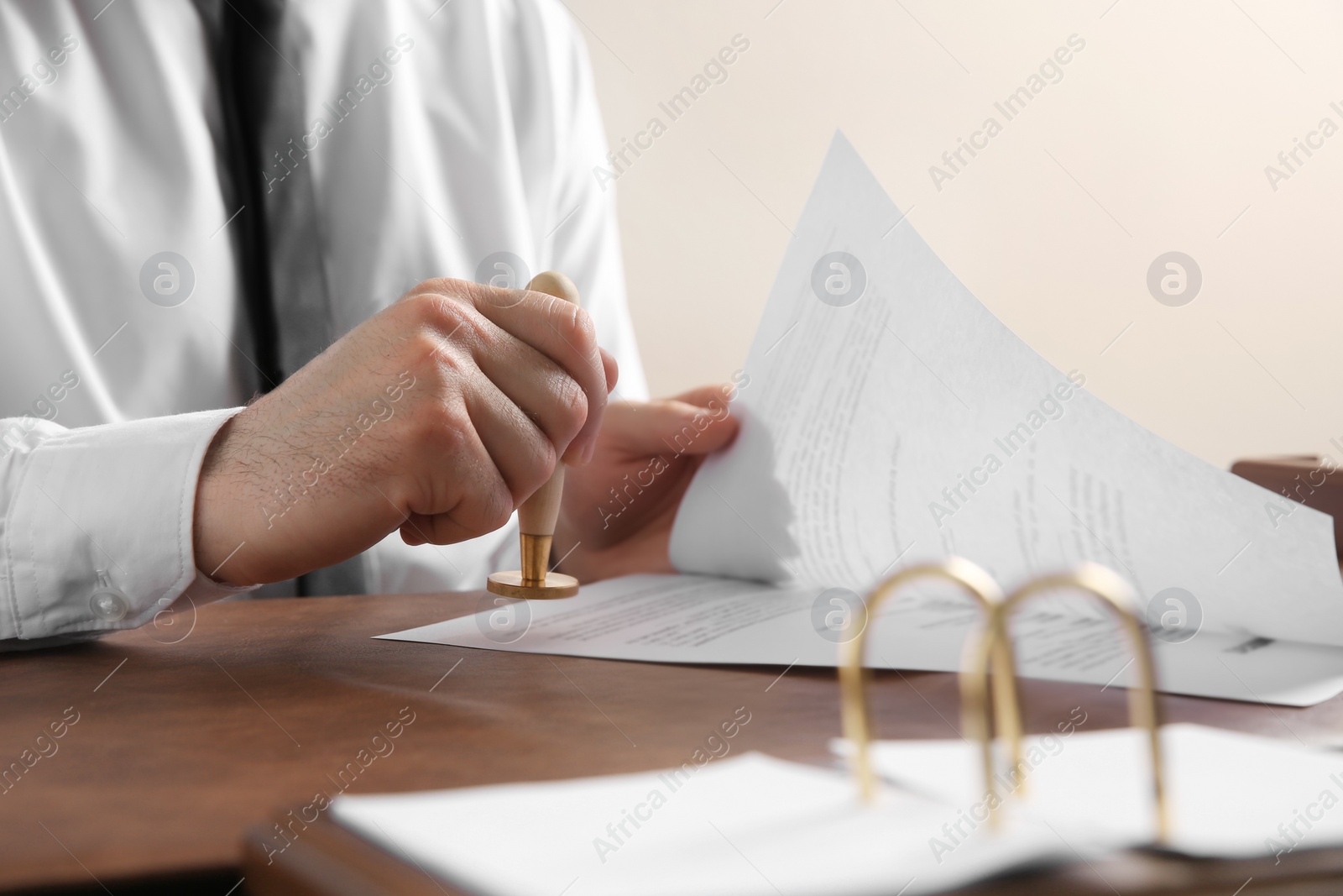 Photo of Male notary stamping document at table, closeup