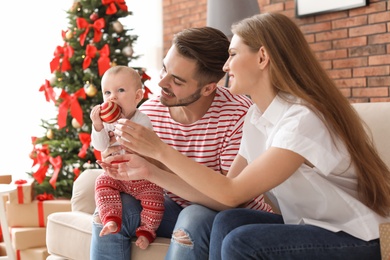 Happy couple with baby celebrating Christmas together at home