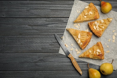 Cut delicious sweet pear tart and knife on dark wooden table, flat lay. Space for text