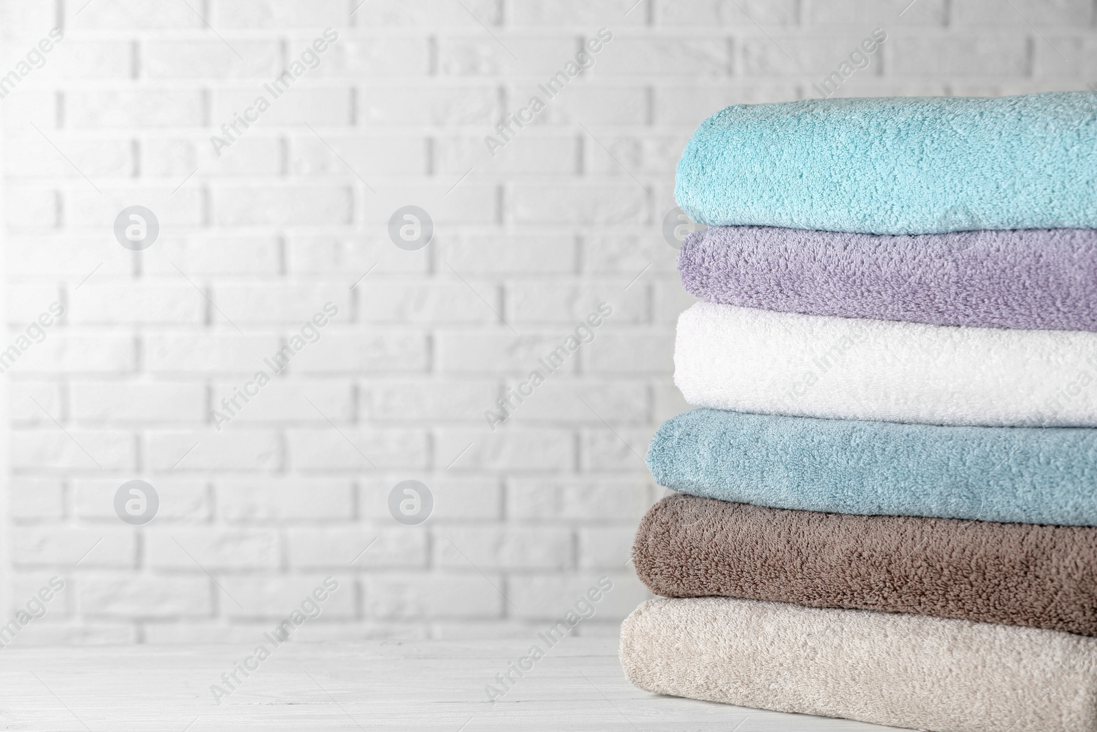 Photo of Stack of clean bath towels on white wooden table. Space for text