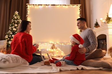 Photo of Family near video projector screen at home. Christmas time