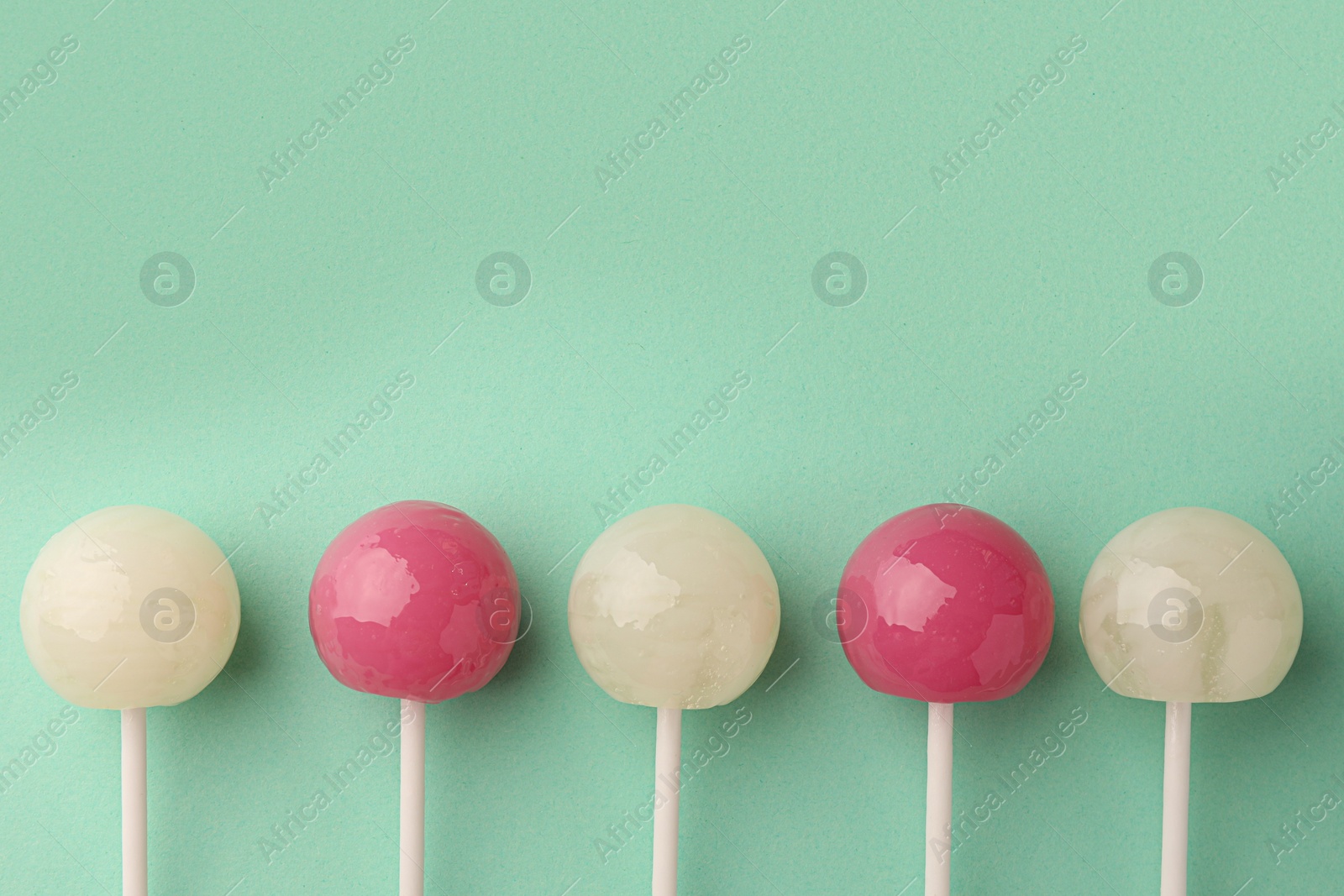 Photo of Tasty lollipops on turquoise background, flat lay. Space for text