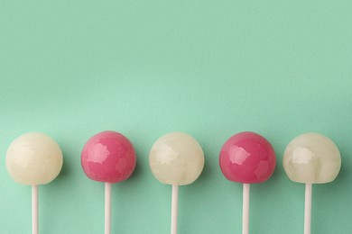 Tasty lollipops on turquoise background, flat lay. Space for text