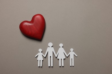 Photo of Paper family figures and red wooden heart on light grey background, flat lay. Insurance concept