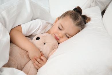Photo of Beautiful little girl sleeping with toy in bed. Bedtime schedule
