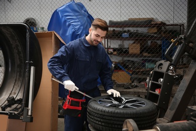 Photo of Technician working with car wheel at automobile repair shop