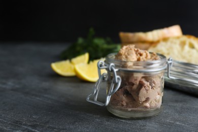 Photo of Glass jar of tasty cod liver on black table, closeup. Space for text