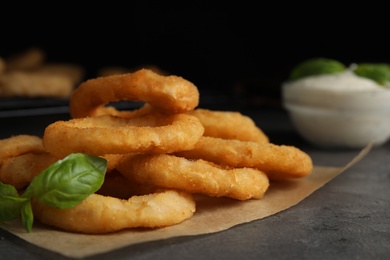 Photo of Fried onion rings served on grey table