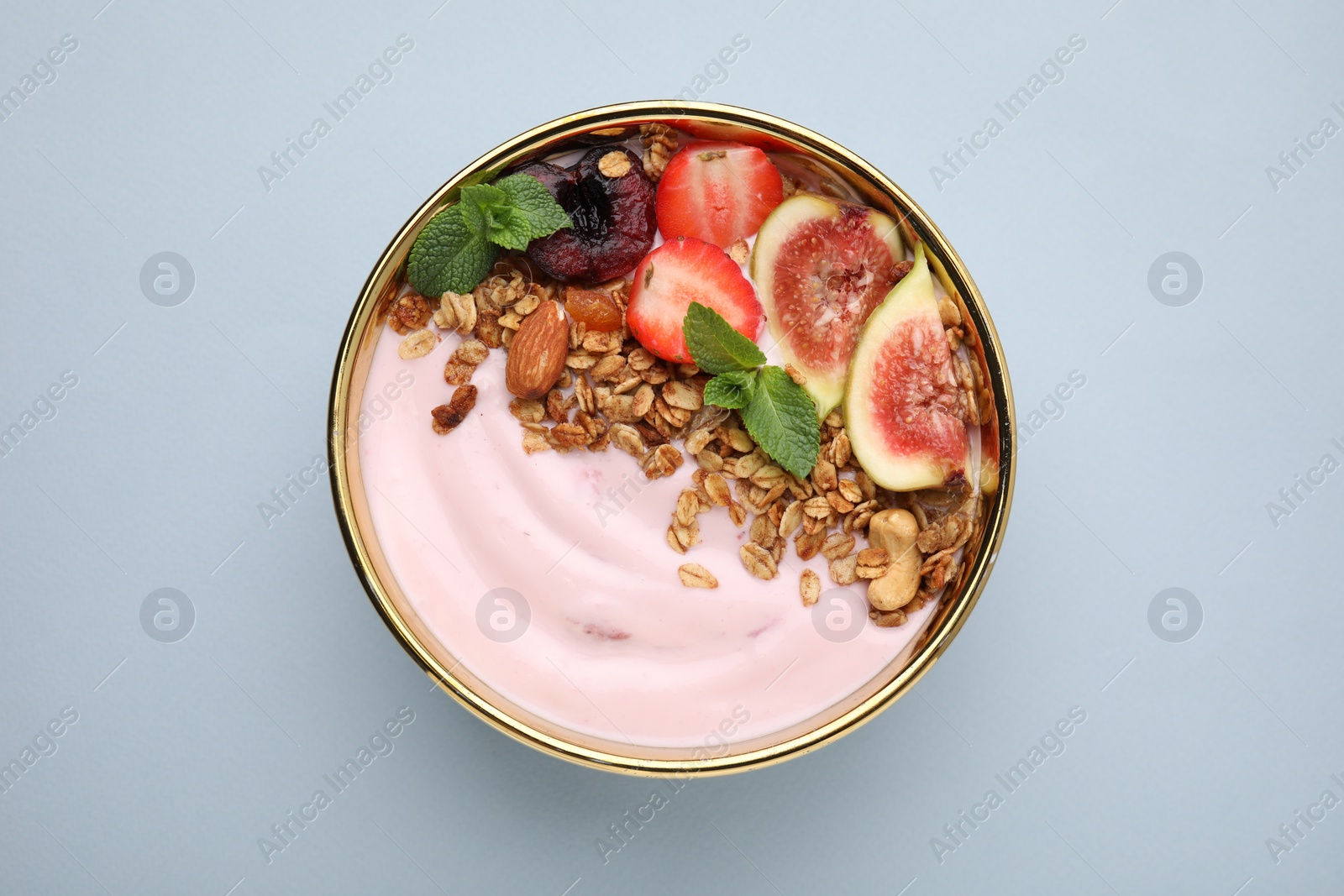 Photo of Bowl with yogurt, fruits and granola on light grey background, top view
