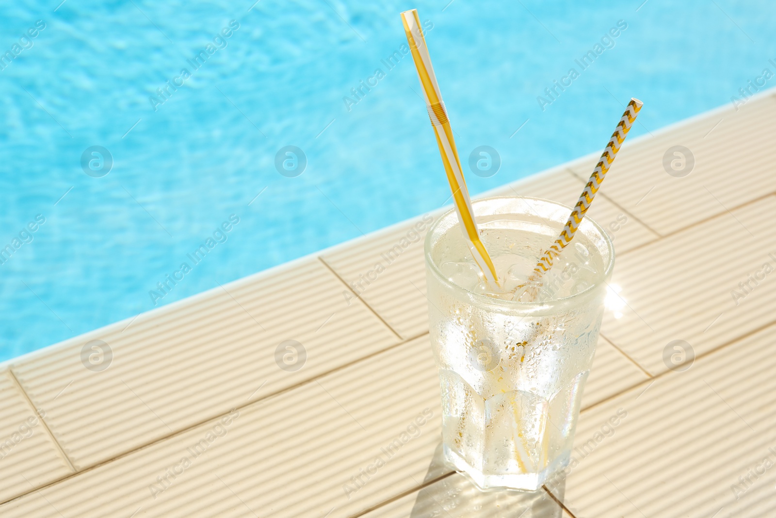 Photo of Glass of refreshing drink near swimming pool. Space for text