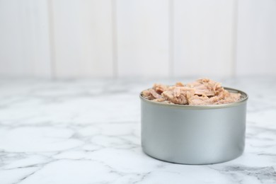 Tin can with canned tuna on white marble table, space for text