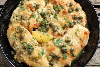 Photo of Delicious chicken piccata with herbs on wooden table, top view