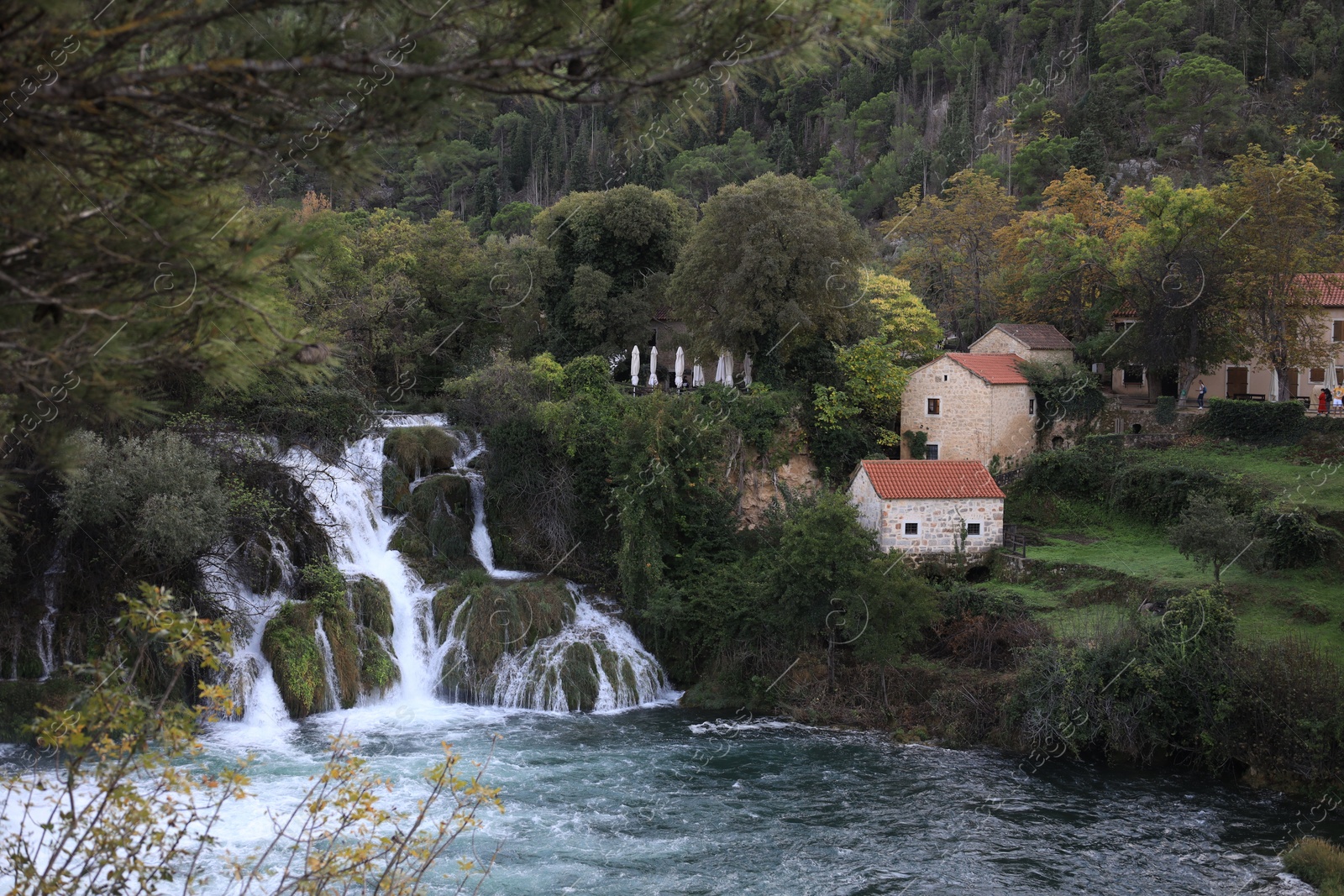 Photo of Picturesque view of beautiful waterfall and buildings outdoors