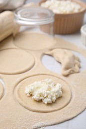 Photo of Process of making dumplings (varenyky) with cottage cheese. Raw dough and ingredients on white table, closeup