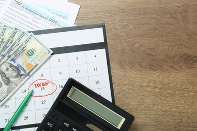 Photo of Calendar with date reminder about tax day, documents, pen, money and calculator on wooden table, flat lay. Space for text