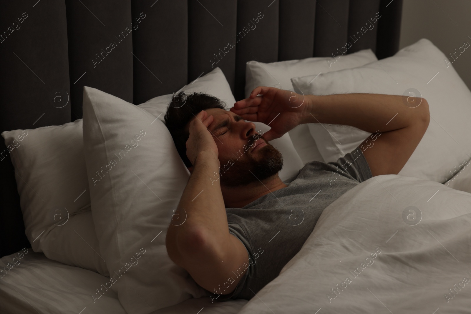 Photo of Man suffering from headache in bed at night