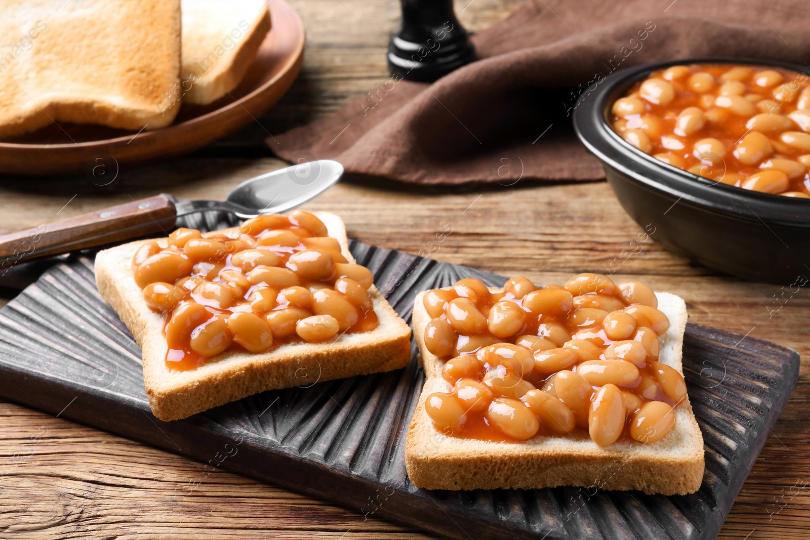 Photo of Toasts with delicious canned beans on wooden table