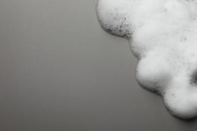 Photo of Fluffy soap foam on grey background, top view. Space for text
