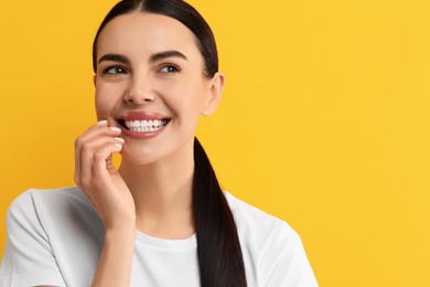 Photo of Beautiful woman with clean teeth smiling on yellow background, space for text