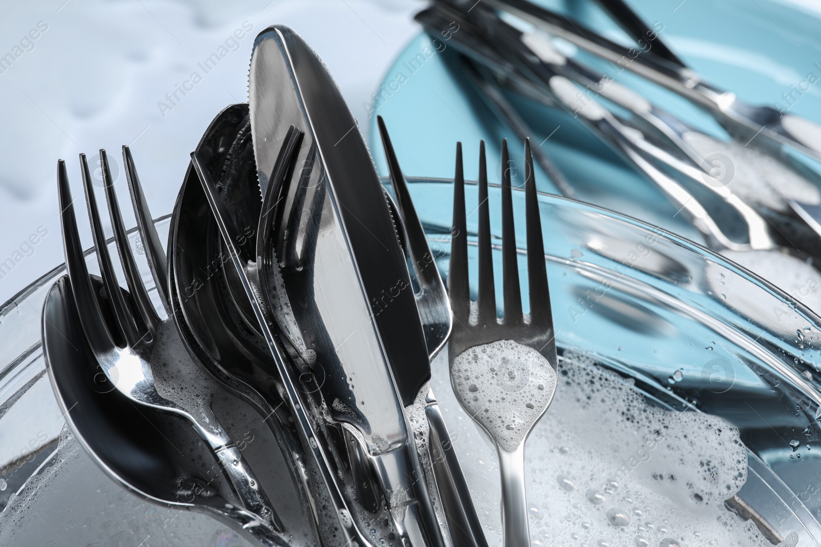 Photo of Glass bowl with silverware in foam, closeup