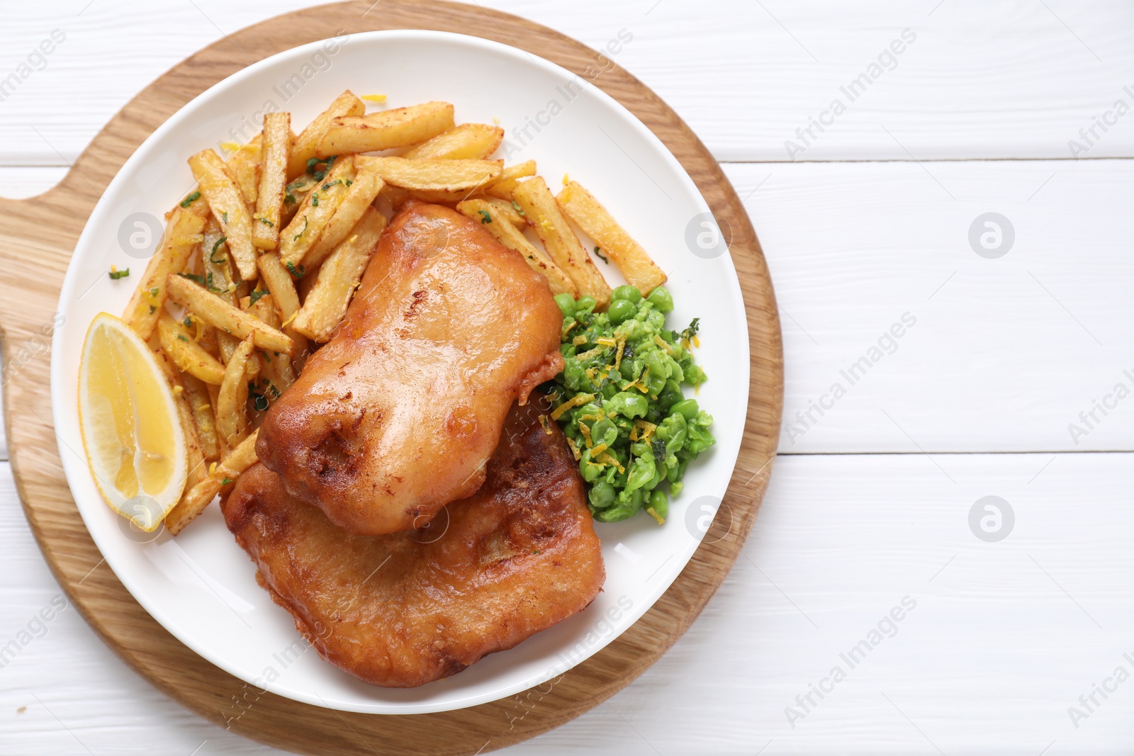 Photo of Tasty fish, chips, peas and lemon on white wooden table, top view