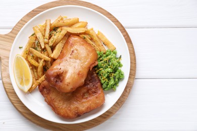 Photo of Tasty fish, chips, peas and lemon on white wooden table, top view