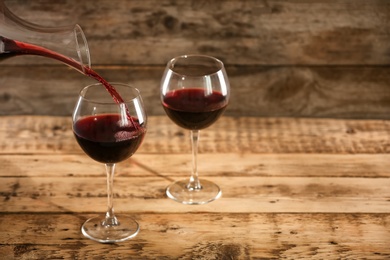 Pouring delicious red wine into glass on table