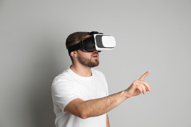 Photo of Man using virtual reality headset on light grey background