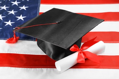 Photo of Graduation hat and diploma on flag of United States