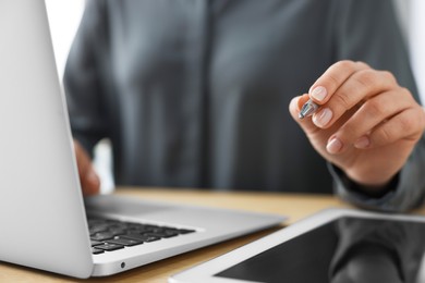 Photo of Woman with tablet and pen working on laptop at wooden table, closeup. Electronic document management