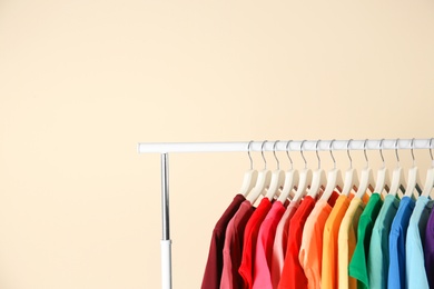 Photo of Many t-shirts hanging in order of rainbow colors on light background