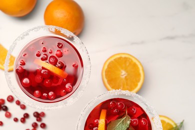 Tasty cranberry cocktail with oranges in glasses on white table, flat lay. Space for text