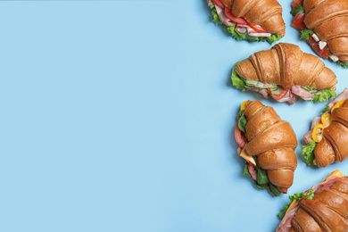 Photo of Croissant sandwiches on light blue background, flat lay. Space for text