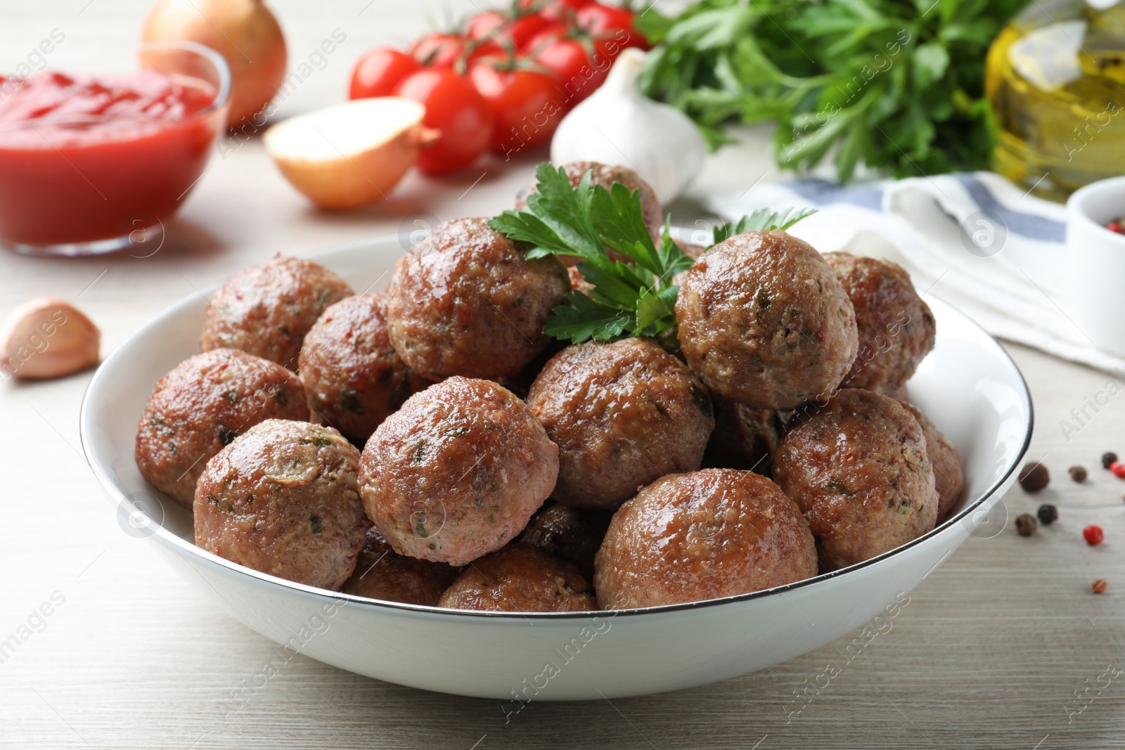 Photo of Tasty cooked meatballs with parsley on white wooden table, closeup