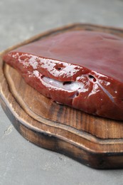 Photo of Piece of raw beef liver on grey table, closeup