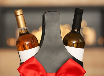 Photo of Festive package with bottles of wine against blurred background, closeup