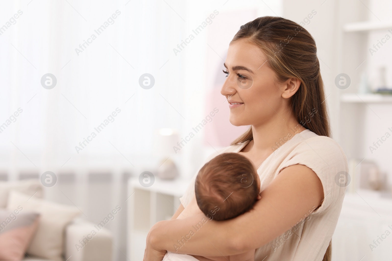 Photo of Mother holding her cute newborn baby in child's room, space for text