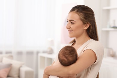 Photo of Mother holding her cute newborn baby in child's room, space for text