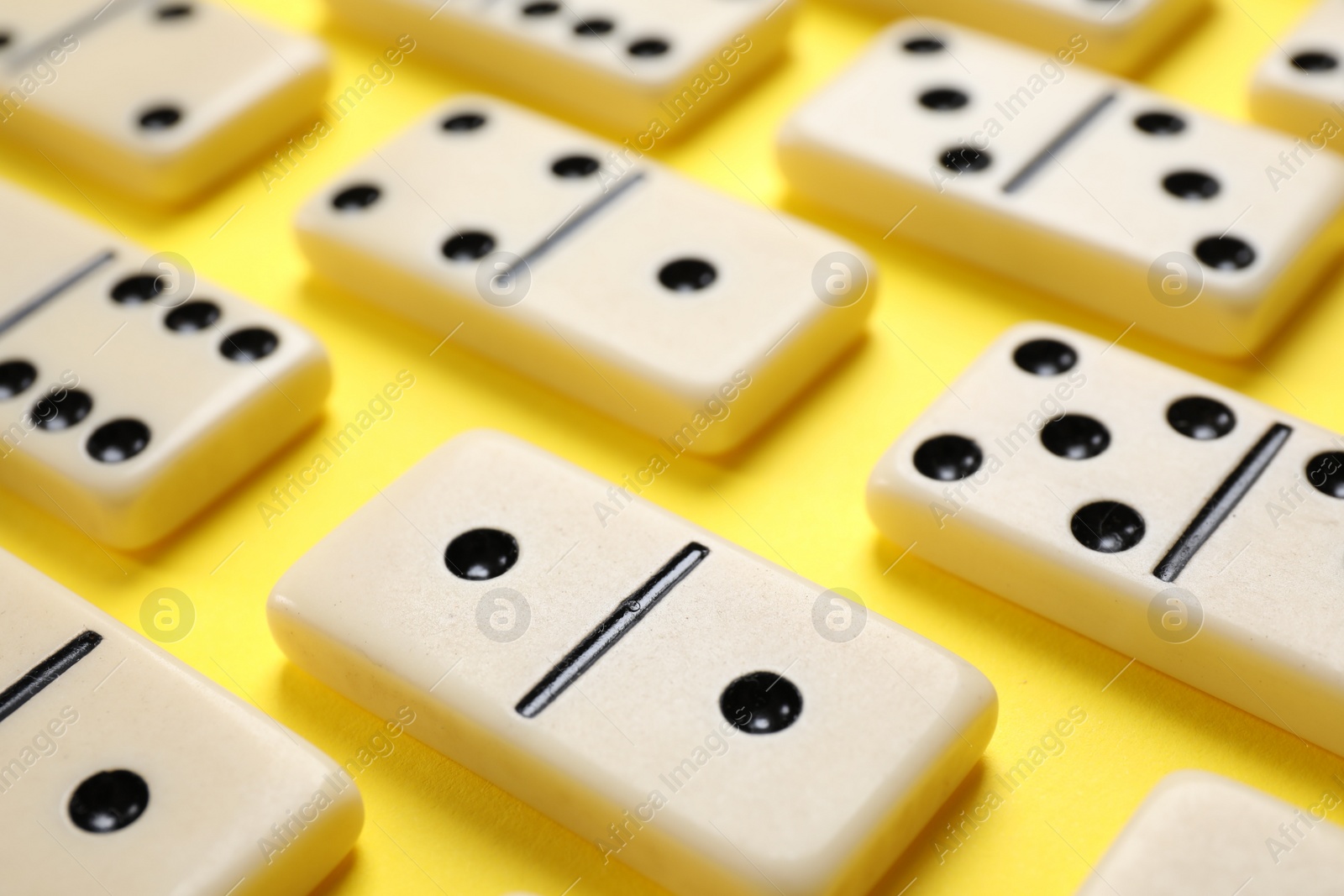 Photo of Classic domino tiles on yellow background, closeup