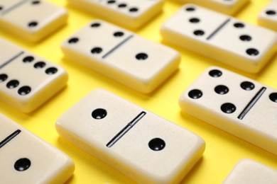 Photo of Classic domino tiles on yellow background, closeup