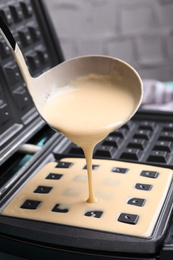 Photo of Pouring dough onto Belgian waffle maker, closeup