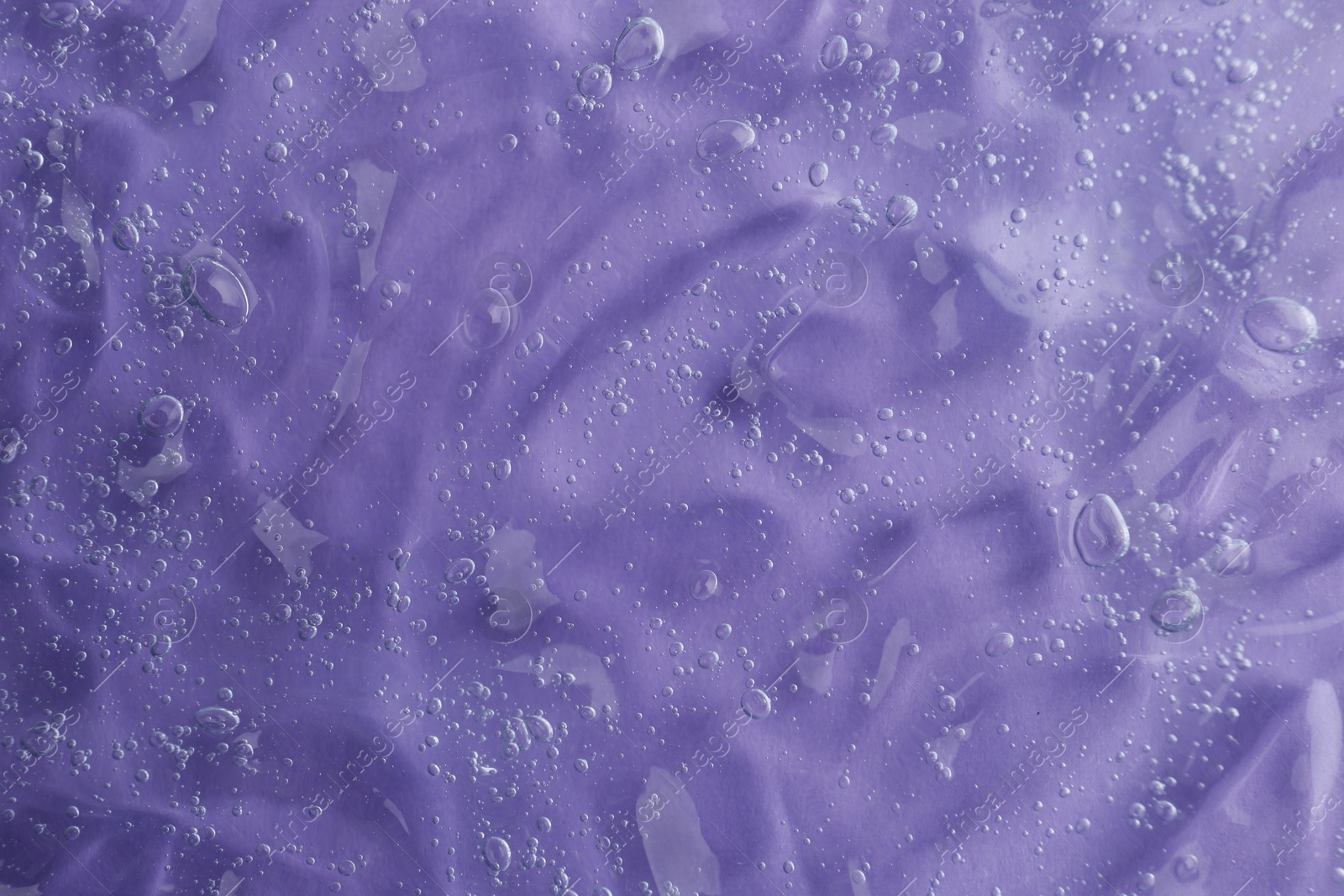 Photo of Texture of transparent shower gel on violet background, closeup