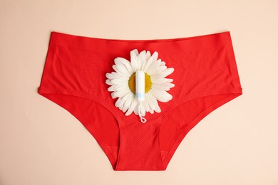 Photo of Tampon, chamomile and panties on beige background, top view