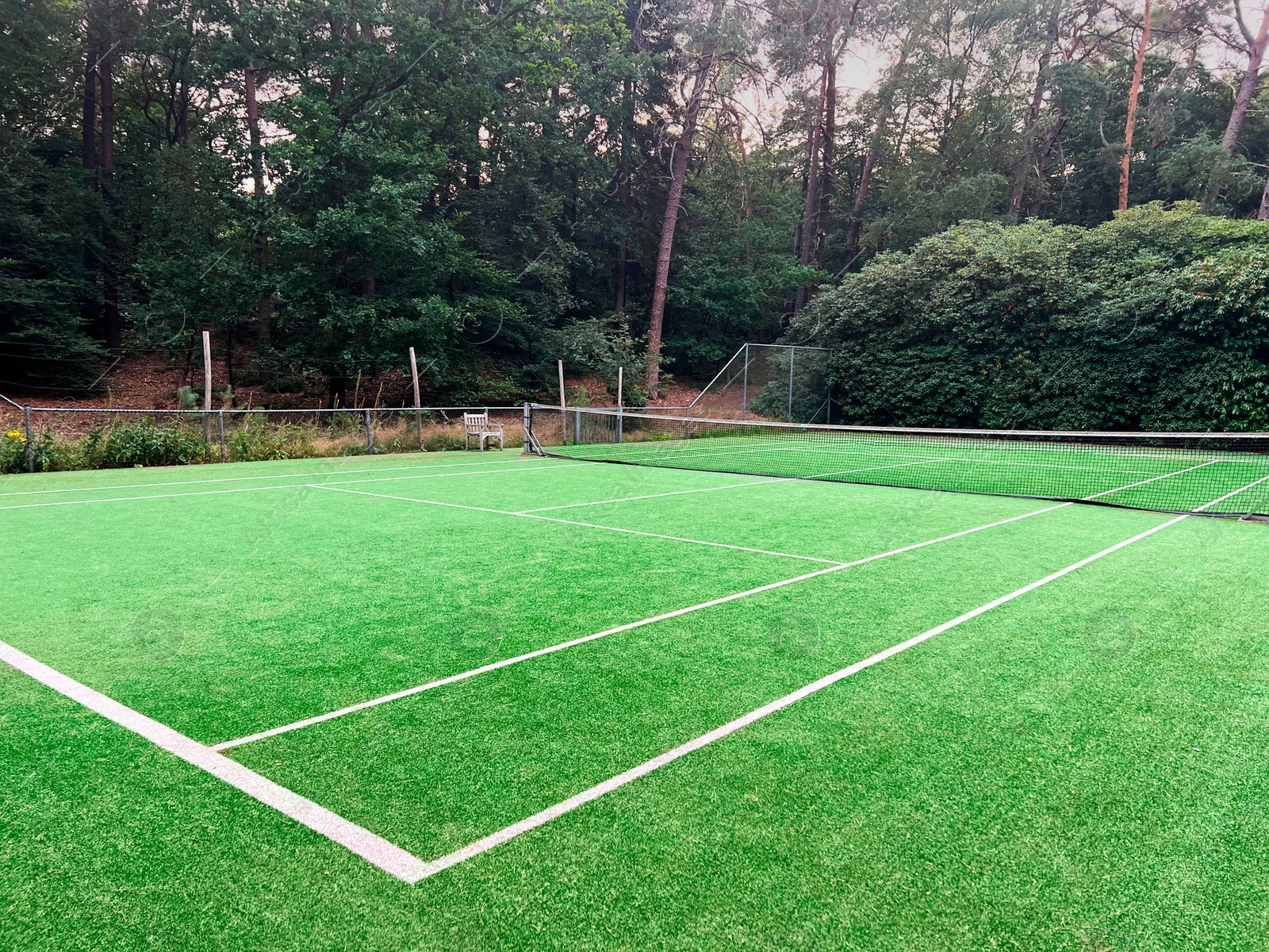 Photo of Tennis court with green grass and net outdoors