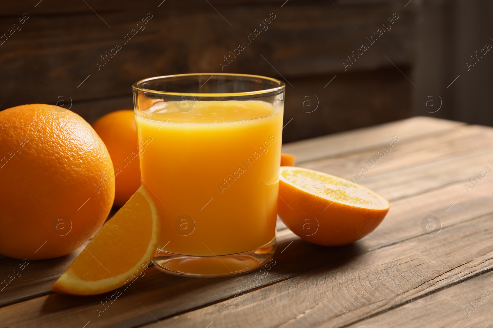 Photo of Glass of orange juice and fresh fruits on wooden table