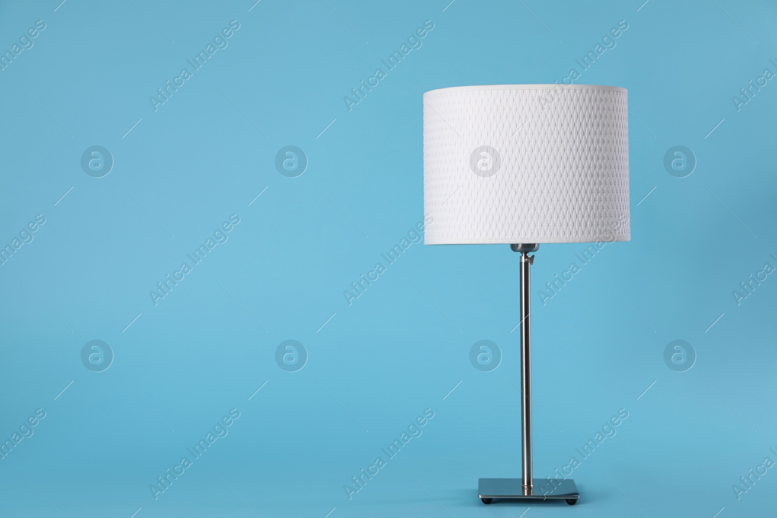 Photo of Stylish new night lamp on light blue background. Space for text