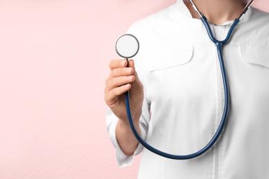 Photo of Doctor with stethoscope on pink background, closeup. Medical service