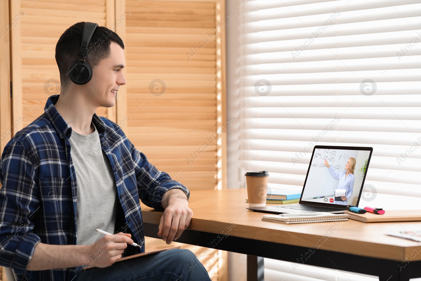 Image of E-learning. Young man having online lesson with teacher via laptop at home